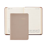 A 2027 daily planner shown open in the background with lined pages, with a closed textured leather cover in front. The cover is a warm taupe-beige color with '2027' embossed in gold.
